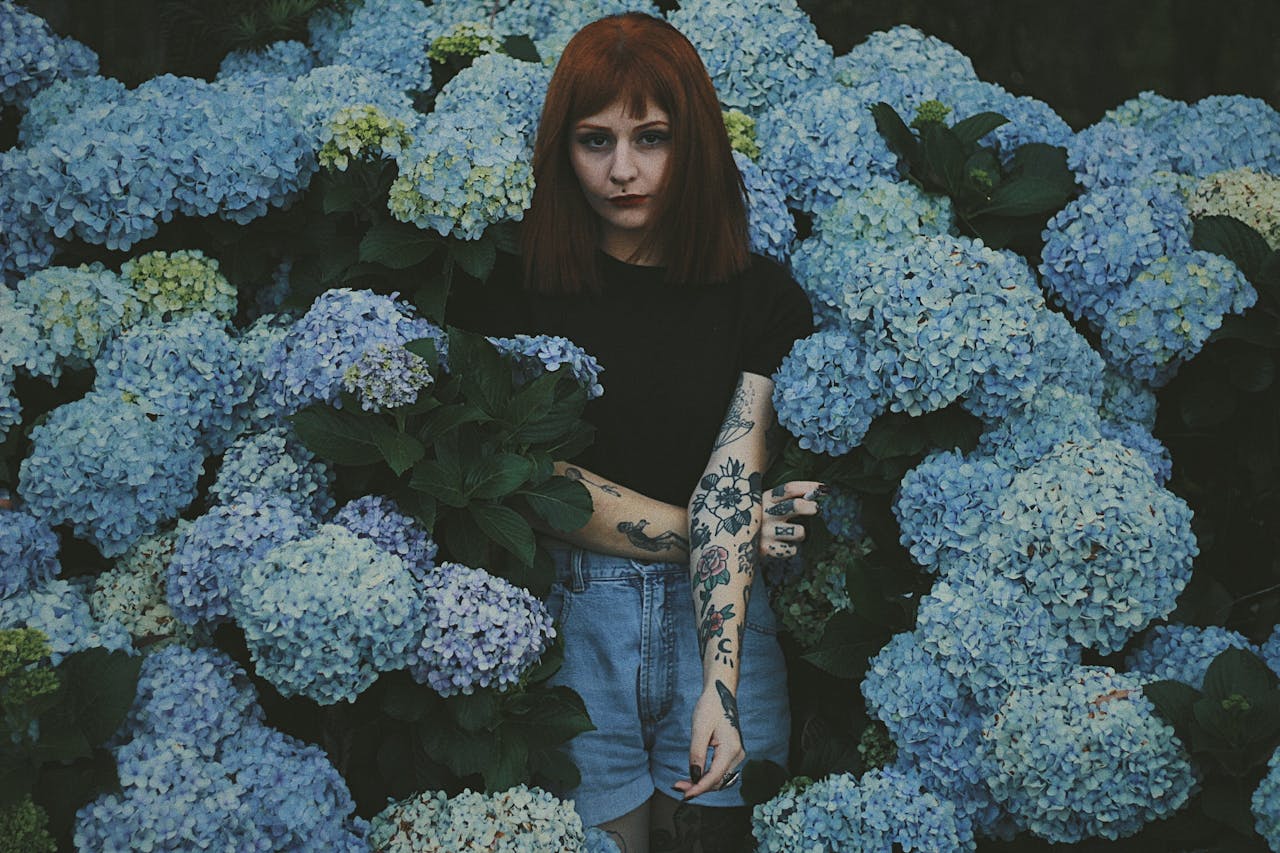 Chica entre flores con tatuajes estilo floral